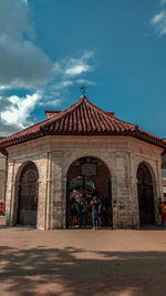 People in front of historic building against blue sky