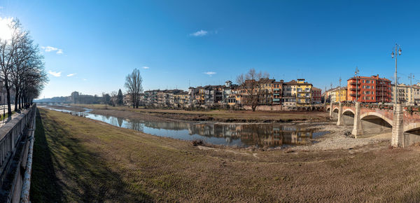 Bridge over river by buildings against blue sky