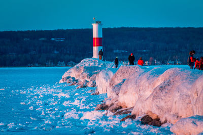 People on lighthouse by sea against sky