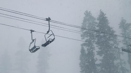 Low angle view of overhead cable car against sky during winter