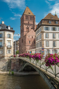 Arch bridge over river amidst buildings against sky