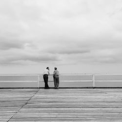 Man standing on pier at sea