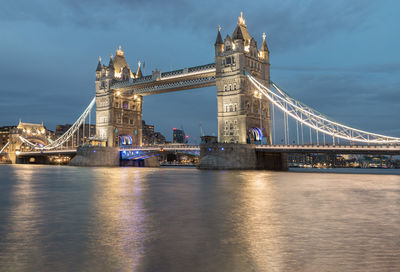 Illuminated bridge over river at night