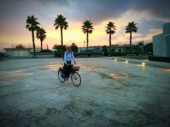 Man riding bicycle on street against sky