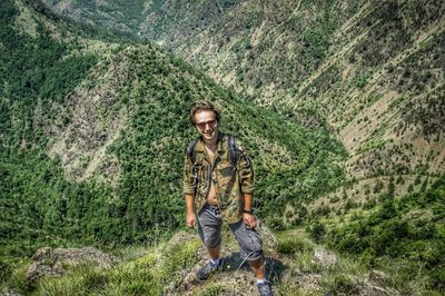 Portrait of smiling young man against tree mountain