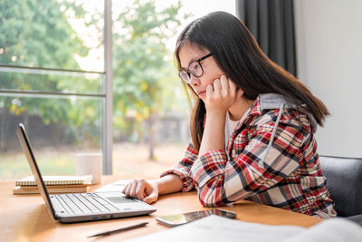 Midsection of woman using mobile phone while sitting on table