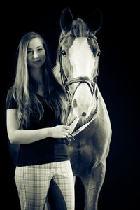 Young woman standing against black background