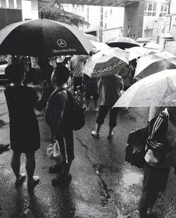 Rear view of people walking on wet street during rainy season