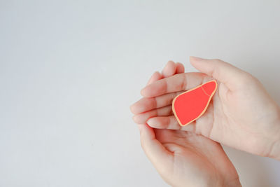 Cropped hand holding heart shape against white background