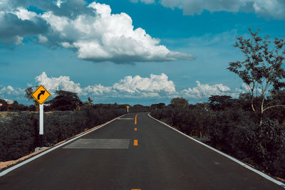 Directional sign by road against sky