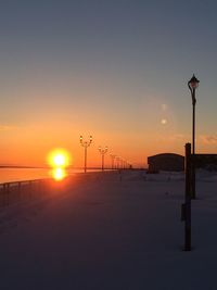 Silhouette street light on sea against clear sky during sunset