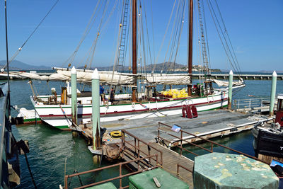 Boats moored at harbor against sky