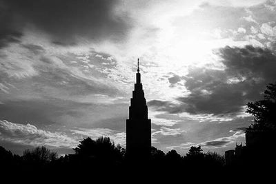 Low angle view of silhouette tower against cloudy sky