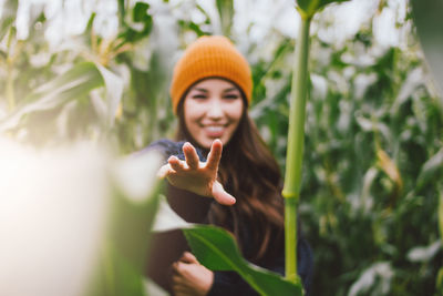 Portrait of smiling young woman standing by plants 