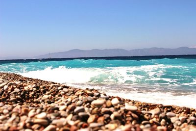 Pebbles on beach against clear sky