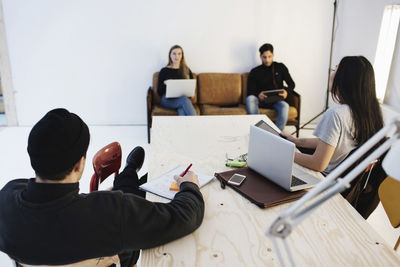 Rear view of four people discussing with colleagues in creative office
