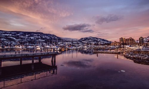 Reflection of snow capped mountains in city at sunset