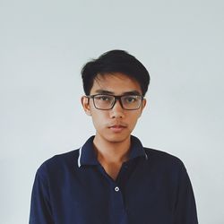 Portrait of young man wearing eyeglasses against white background