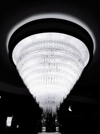 Low angle view of illuminated lighting equipment hanging against sky