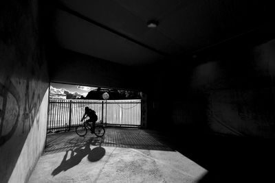 Rear view of man riding bicycle in tunnel