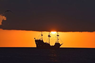 Silhouette ship on sea against clear sky during sunset