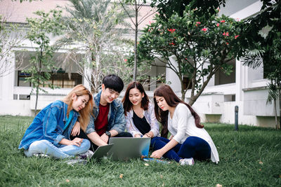 Young woman using phone while sitting on grass