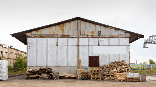 A large metal industrial warehouse for storing goods, next to it are wooden pallets for storing 