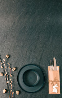 Empty plates with a knife, fork and easter decorations on a black background.