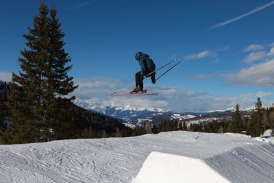 Man jumping on snowcapped mountain against sky