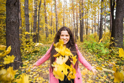 Portrait of smiling young woman in forest during autumn