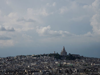 Buildings in city against cloudy sky