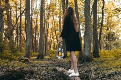 Full length of woman with oil lamp standing in forest