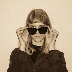 Portrait of young woman wearing sunglasses against white background