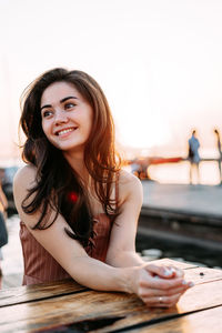 Portrait of smiling young woman against sky