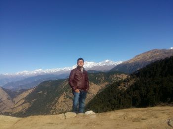 Full length of man standing on mountain against clear blue sky