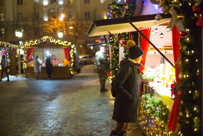 Rear view of woman walking on street at night