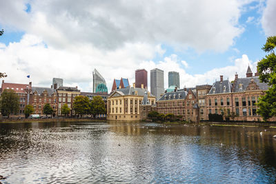 Buildings in city against cloudy sky with waterfront