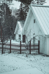 Snow covered field by trees and building