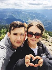 Portrait of smiling young man and woman against mountains