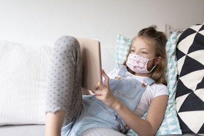 Girl using mobile phone on sofa at home