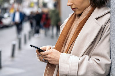 Midsection of woman using mobile phone outdoors