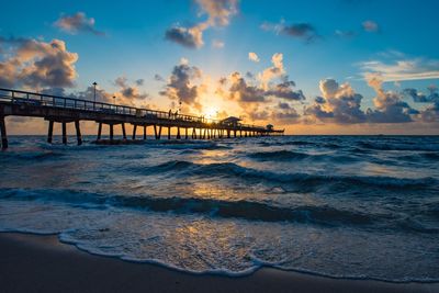 Bridge over sea against sky during sunset