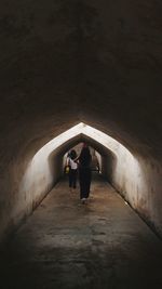 Rear view of people walking in tunnel