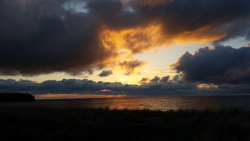 Scenic view of sea against dramatic sky during sunset