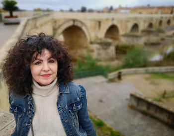 Portrait of woman standing against bridge