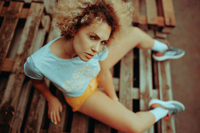 High angle portrait of happy woman sitting on wood