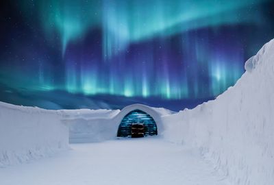 Snow covered landscape against sky at night during winter