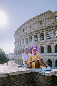 People sitting at historical building against sky