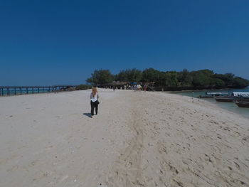 Woman walking on beach against clear sky