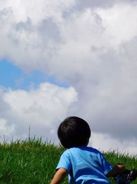 Rear view of boy on field against sky